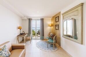 A hotel room with a balcony, a dining area, a sofa, and a large mirror. - Boutique Hotel Liberata (L'Île-Rousse)