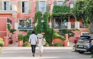 Un edificio residencial con balcones, una escalera y un automóvil estacionado.