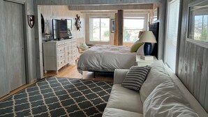 Ein Schlafzimmer mit Bett, Kommode, Fernseher und Deckenventilator.