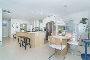 A modern kitchen with a central island, bar stools, a dining table with chairs, and a refrigerator. - Private Siesta Key Escape — Updated 2‑Bedroom Home Just Minutes from the Sand (Siesta Key)