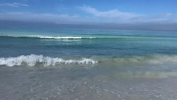 Une plage avec des vagues et un ciel dégagé.