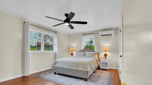 A bedroom with a bed, two bedside lamps, a ceiling fan, and a window with curtains. - Hickory Ridge Homestead | Free Farm Tours + Firepit (Augusta)