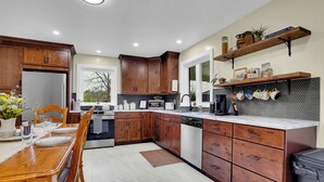 A modern kitchen with wooden cabinets, a dining table, and a built-in oven. - Hickory Ridge Homestead | Free Farm Tours + Firepit (Augusta)