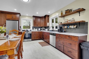 A modern kitchen with wooden cabinets, a dining table, and a built-in oven. - Hickory Ridge Homestead | Free Farm Tours + Firepit (Augusta)