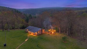 A house with a well-maintained lawn, a visible chimney emitting smoke, and a clear sky. - Hickory Ridge Homestead | Free Farm Tours + Firepit (Augusta)