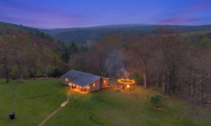 A house with a well-maintained lawn, a visible chimney emitting smoke, and a clear sky. - Hickory Ridge Homestead | Free Farm Tours + Firepit (Augusta)