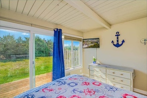 Une chambre à coucher avec un lit, une commode, une télévision et une vue sur l’extérieur.