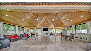 An indoor space with a high ceiling, wooden beams, a central fireplace, and seating arrangements. - Welcome to your Private Tampa escape — designed for unforgettable group stays! (Tampa)