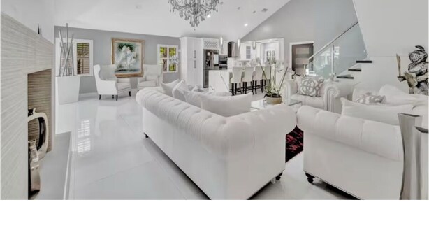 A modern living room with a large white sofa, a chandelier, and a staircase. - Welcome to your Private Tampa escape — designed for unforgettable group stays! (Tampa)