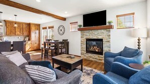 A living room with a fireplace, a dining area, wooden cabinets, and a TV mounted on the wall. - Waterfront Dover Bay House: Walk to Marina & (Dover)