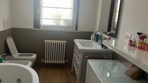 Ein Badezimmer mit Toilette, Waschbecken, Spiegel und Fenster.