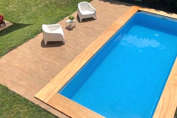 A rectangular swimming pool with a wooden deck and two white lounge chairs. - Nice Villa With Pool and Garden (Fermignano)