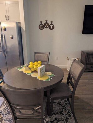 Una mesa de comedor con un cuenco de limones, un portalápices y un letrero en la pared que dice 'EAT'.