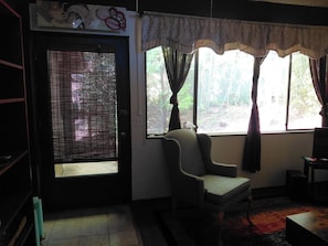 Ein Zimmer mit Fenster, Stuhl und Tür.