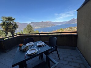 Ein Tisch für zwei auf einem Balkon mit Blick auf Berge und einen See.