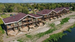A row of modern cabins with large windows, wooden decks, and a river view. - Water's Edge Wellness Retreat With Sauna (Workum)
