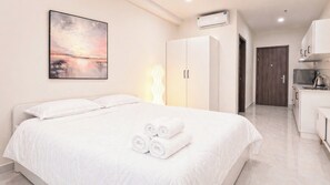 Ein Hotelzimmer mit Bett, Schrank, Küchenzeile und Klimaanlage.