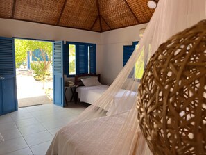 Una habitación con cama, una mesita y una ventana con contraventanas azules.