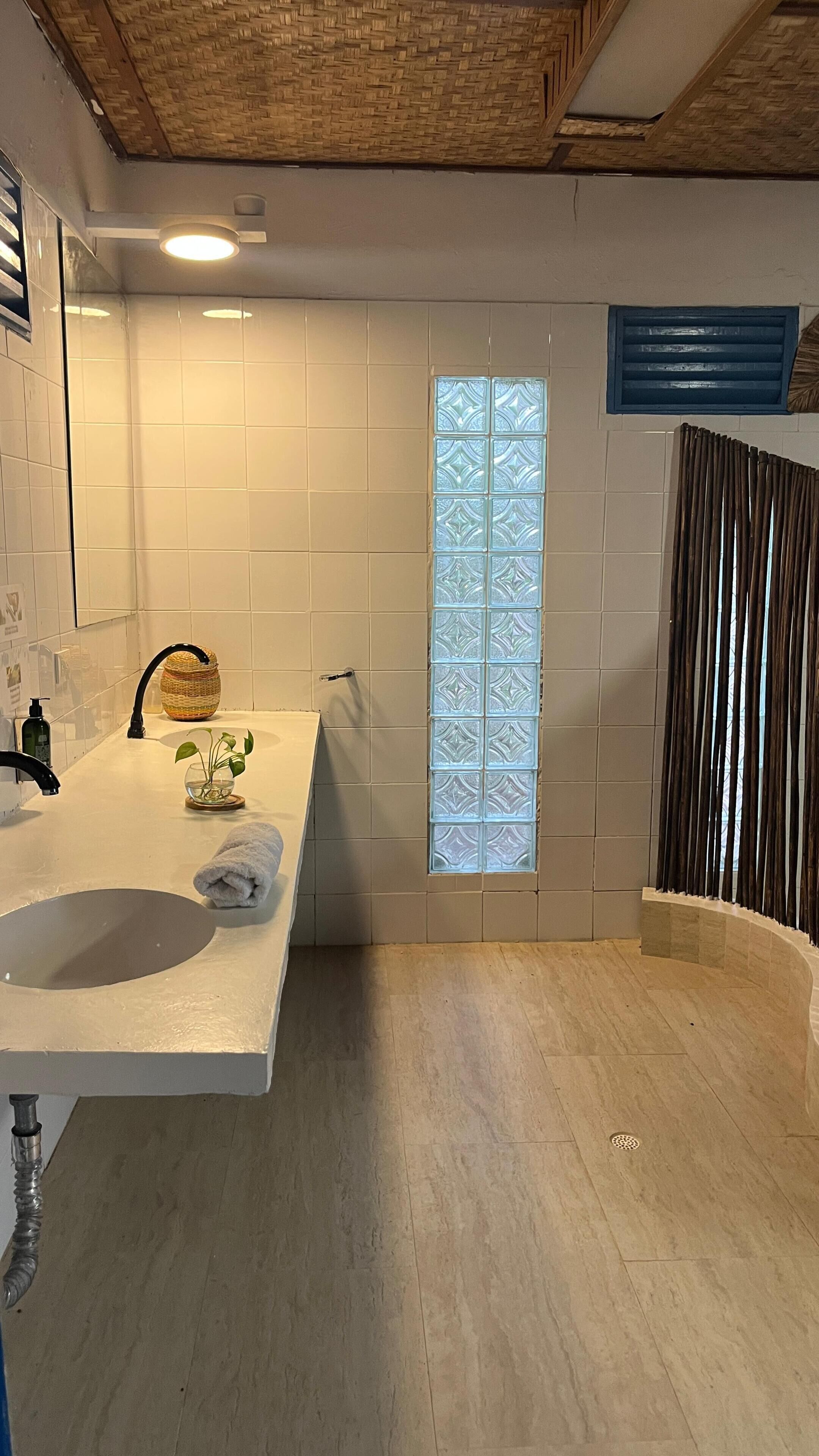 Un baño con un lavabo grande de color blanco, cabina de ducha con paredes de vidrio y una ventana con vidrio esmerilado.