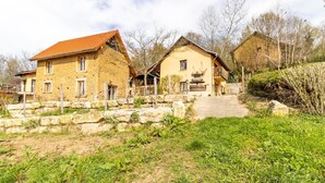 Una casa rústica con un camino de piedra que lleva a la entrada, rodeada de vegetación.