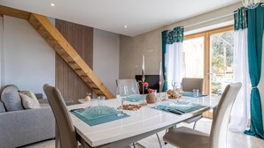 Un comedor con una mesa preparada para cuatro personas, un sofá y un televisor al fondo.