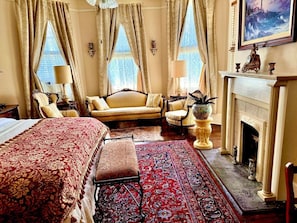 A traditional room with a bed, sofa, and fireplace.