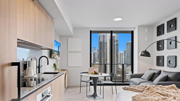 Um apartamento moderno com cozinha, sala de jantar e sala de estar, com uma grande janela e vista para a cidade.