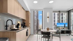 Une cuisine moderne avec un coin repas, de grandes fenêtres et une vue sur le paysage urbain.