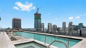 Une piscine sur le toit offrant une vue panoramique sur la ville, avec notamment un immeuble en construction.