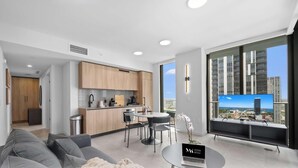 Un appartement moderne doté d’une cuisine, d’un coin repas et d’une grande fenêtre offrant une vue sur la ville.