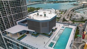 Un edificio alto con piscina en la azotea y vistas a un puerto deportivo.