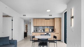Una cucina moderna con mobili in legno, un tavolo rotondo e sedie nere.