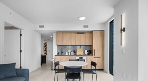 A modern kitchen with wooden cabinets, a round dining table, and black chairs. - 501 First #3301|2BR w/ WaterView near Cruise Lines (Miami)