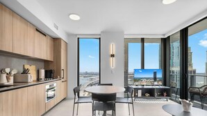 Una cucina moderna con pensili in legno, un'area pranzo con un tavolo rotondo e sedie, e un'ampia finestra che offre vista sulla città.