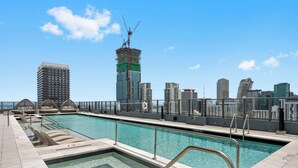 Una piscina sul tetto con vista sullo skyline cittadino, inclusa una costruzione in corso.