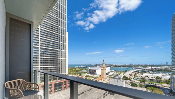 Een balkon met uitzicht op een stadsgezicht, waaronder een opvallend gebouw met een toren.