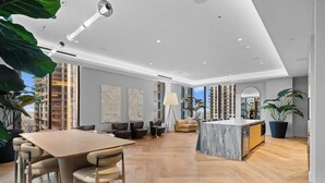 Un intérieur moderne comprenant un coin repas, des canapés, un îlot de cuisine et de grandes fenêtres.