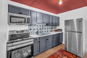 Eine moderne Küche mit grauen Schränken, Edelstahlgeräten, einer Mikrowelle, einem Backofen und einem Kühlschrank.