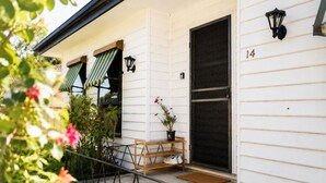 Ein Haus mit einer Veranda, einer Tür mit Hausnummer und einer kleinen Bank.