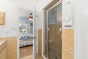 Ein Badezimmer mit Dusche, einem Bett und einem Deckenventilator.