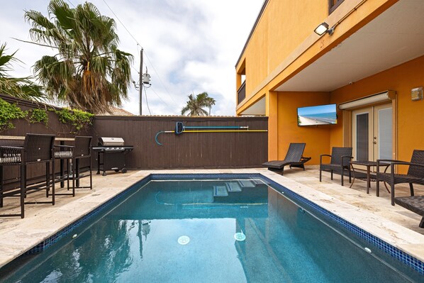 A swimming pool with lounge chairs and a television screen. - Spacious Townhouse • Private Pool • 2 Minute Walk to the Beach (South Padre Island)