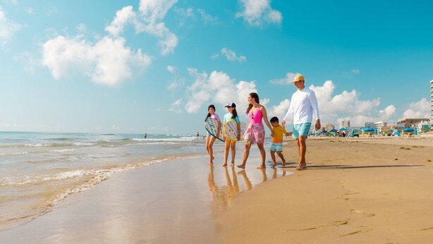 A beach with a clear sky, people walking, and buildings in the background. - Spacious Townhouse • Private Pool • 2 Minute Walk to the Beach (South Padre Island)
