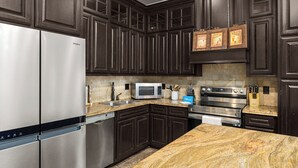 A modern kitchen with dark wood cabinets, stainless steel appliances, granite countertops, and a built-in microwave. - Spacious Townhouse • Private Pool • 2 Minute Walk to the Beach (South Padre Island)