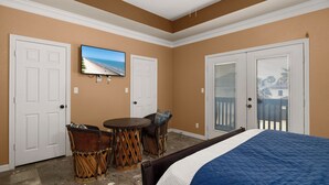 A bedroom with a bed, two doors, a television, and a small table with chairs. - Spacious Townhouse • Private Pool • 2 Minute Walk to the Beach (South Padre Island)