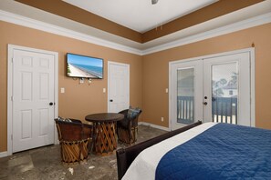 A bedroom with a bed, two doors, a television, and a small table with chairs. - Spacious Home w/ Pool, 1/2 Block to Beach (South Padre Island)