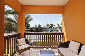 A balcony with wicker furniture and a view of a residential area. - Spacious Home w/ Pool, 1/2 Block to Beach (South Padre Island)