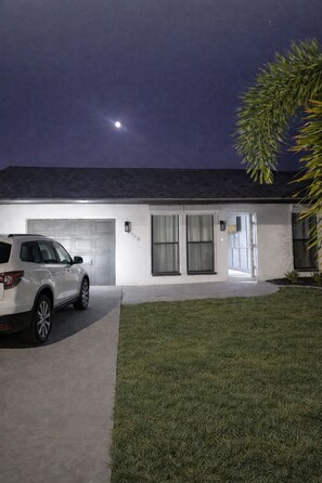 Ein zweistöckiges Haus mit Garage, Auffahrt und Rasenfläche.