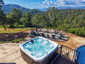 A hot tub surrounded by outdoor seating and a pool, set against a mountainous backdrop. - New! Yosemite Starsong with pool/hot tub/EV/huge views (Coarsegold)