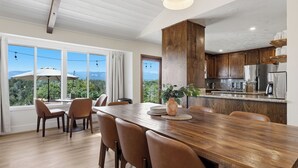 A modern kitchen with wooden cabinets, stainless steel appliances, and a dining area with a large wooden table and chairs. - New! Yosemite Starsong with pool/hot tub/EV/huge views (Coarsegold)