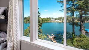 Ein Zimmer mit großem Fenster und Blick auf einen See, umgeben von Bäumen.